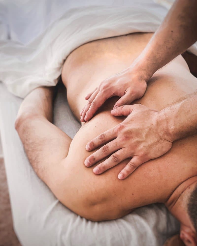 Licensed massage therapist performing focused therapeutic massage techniques on a guest's upper back at The Knotstop spa in San Diego.