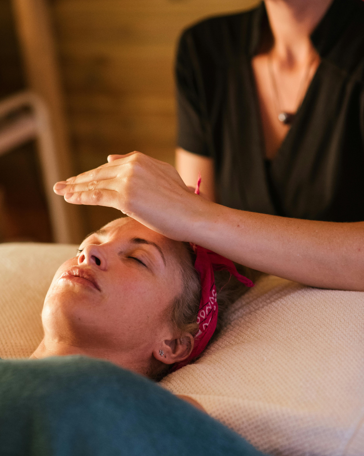 Therapist using gentle Craniosacral Massage techniques beneath a guest's head at The Knotstop in San Diego