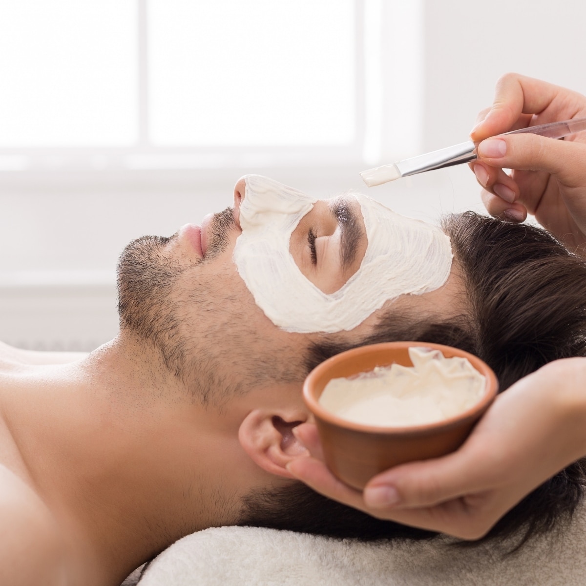 Man receiving a professionally applied facial mask treatment